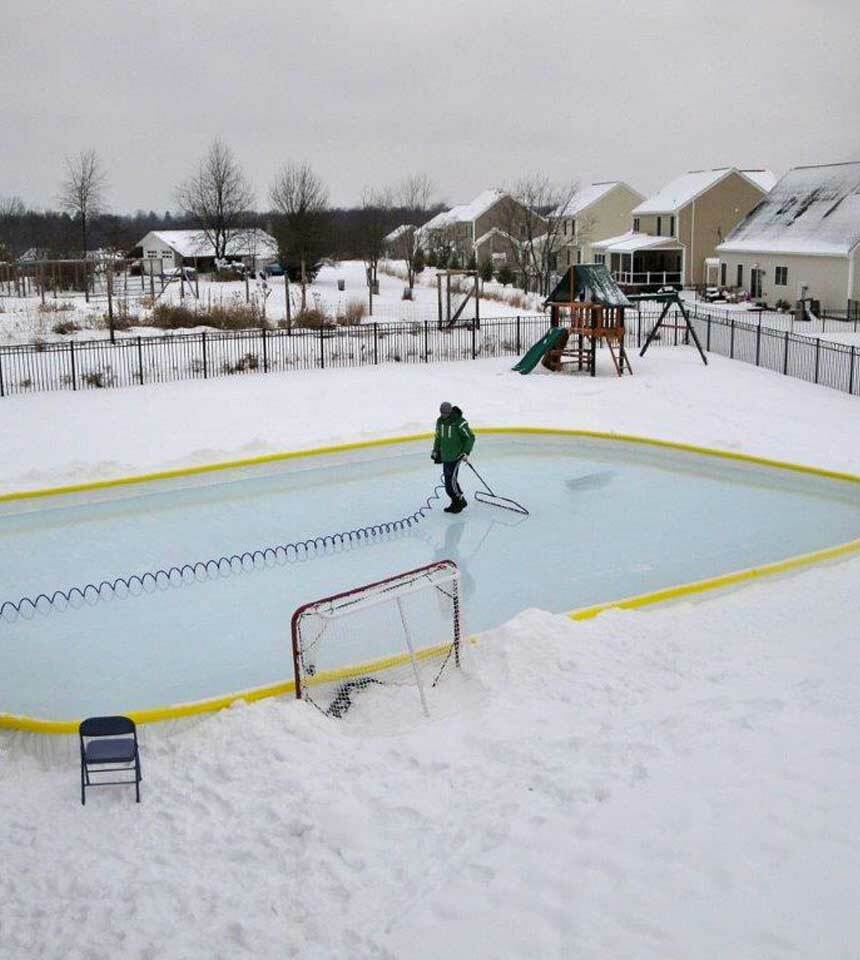 Man smoothing a backyard ice rink surface with a 52" NiceIce™ Resurfacer and a coil  hose