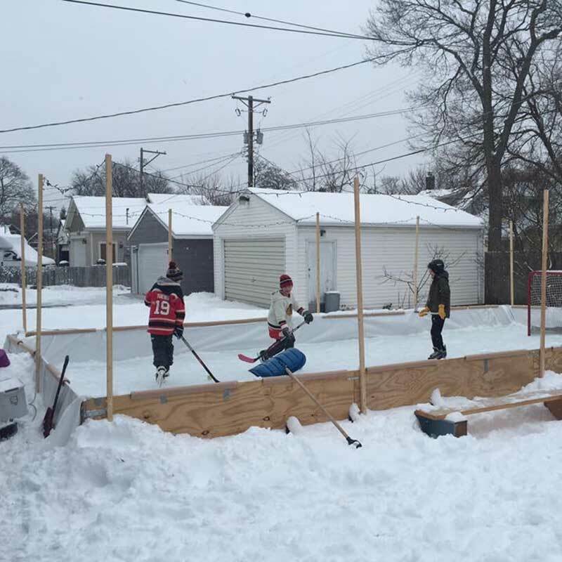 Kids playing in a backyard rink built using the Rink in a Box kit 